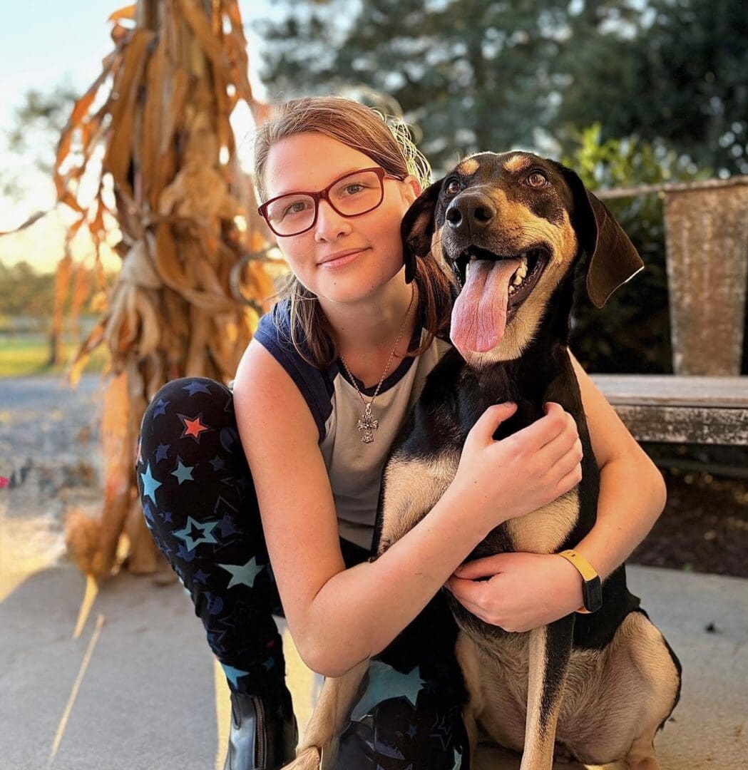 Young woman hugging happy dog outdoors