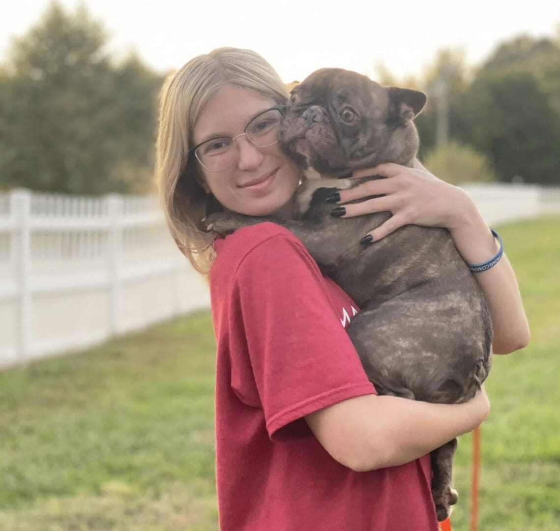 Young woman holding brindle French bulldog outdoors