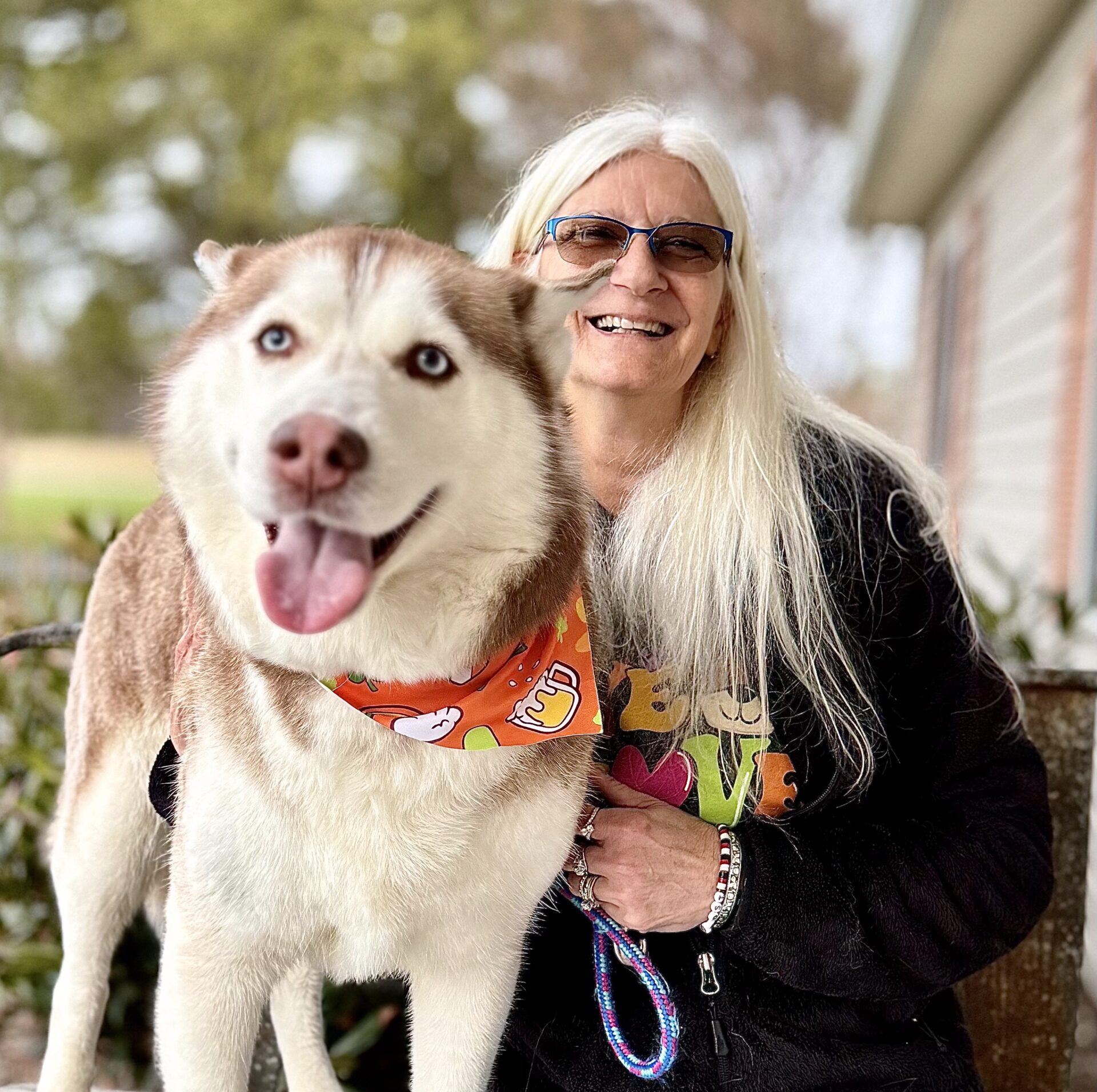 Smiling woman with husky wearing orange bandana