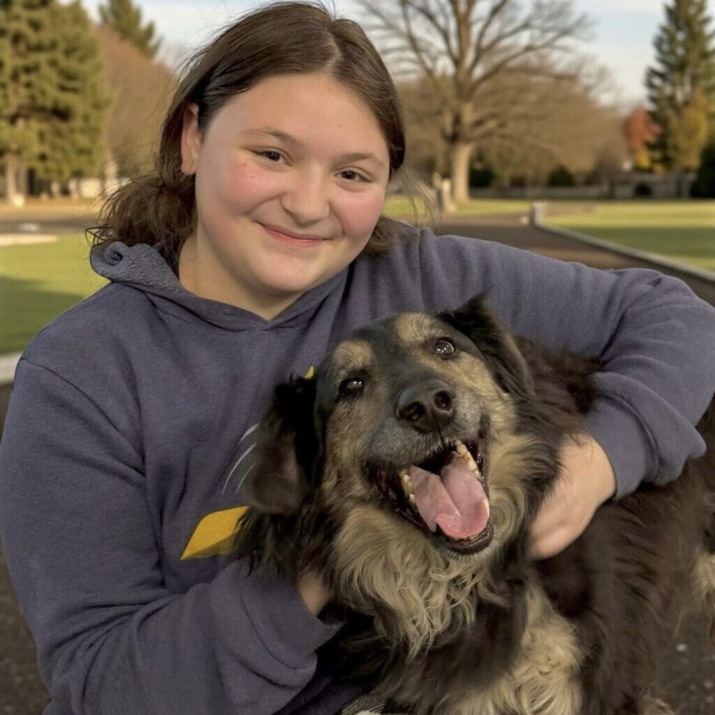Smiling person hugging happy dog in park